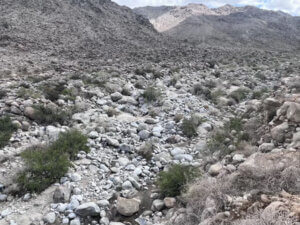 Dry rocky desert wash under cloudy sky