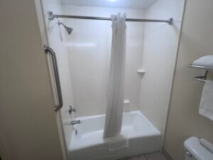 Shower curtain draped into tub with towel