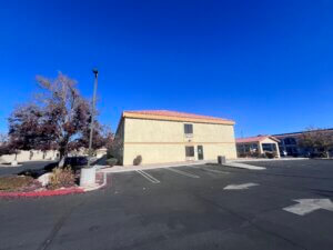 Tan stucco motel, empty parking, vivid sky