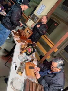 Person hand-rolling cigars at vendor table